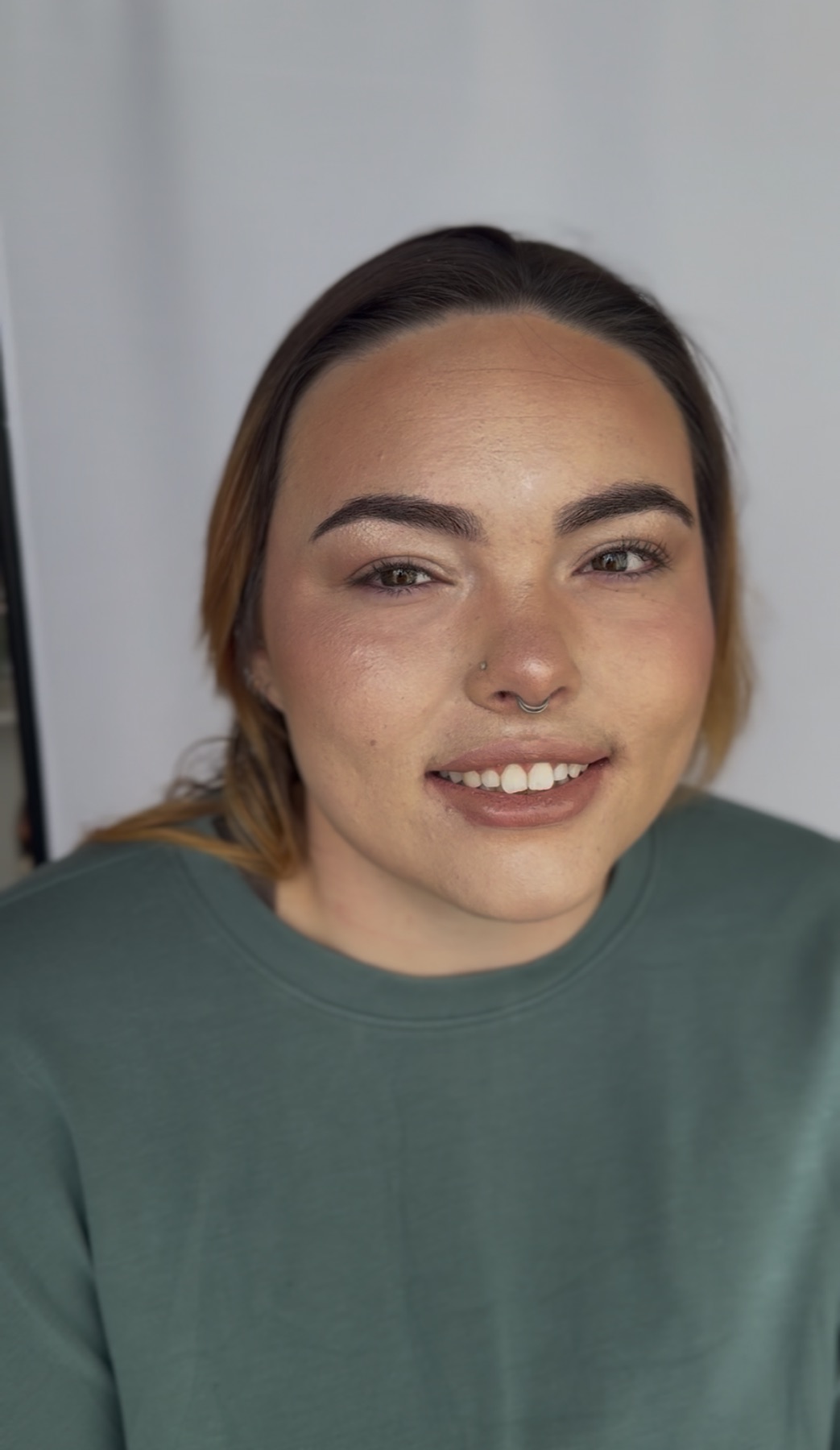 Fresh, glowing event makeup on a client in a green sweater