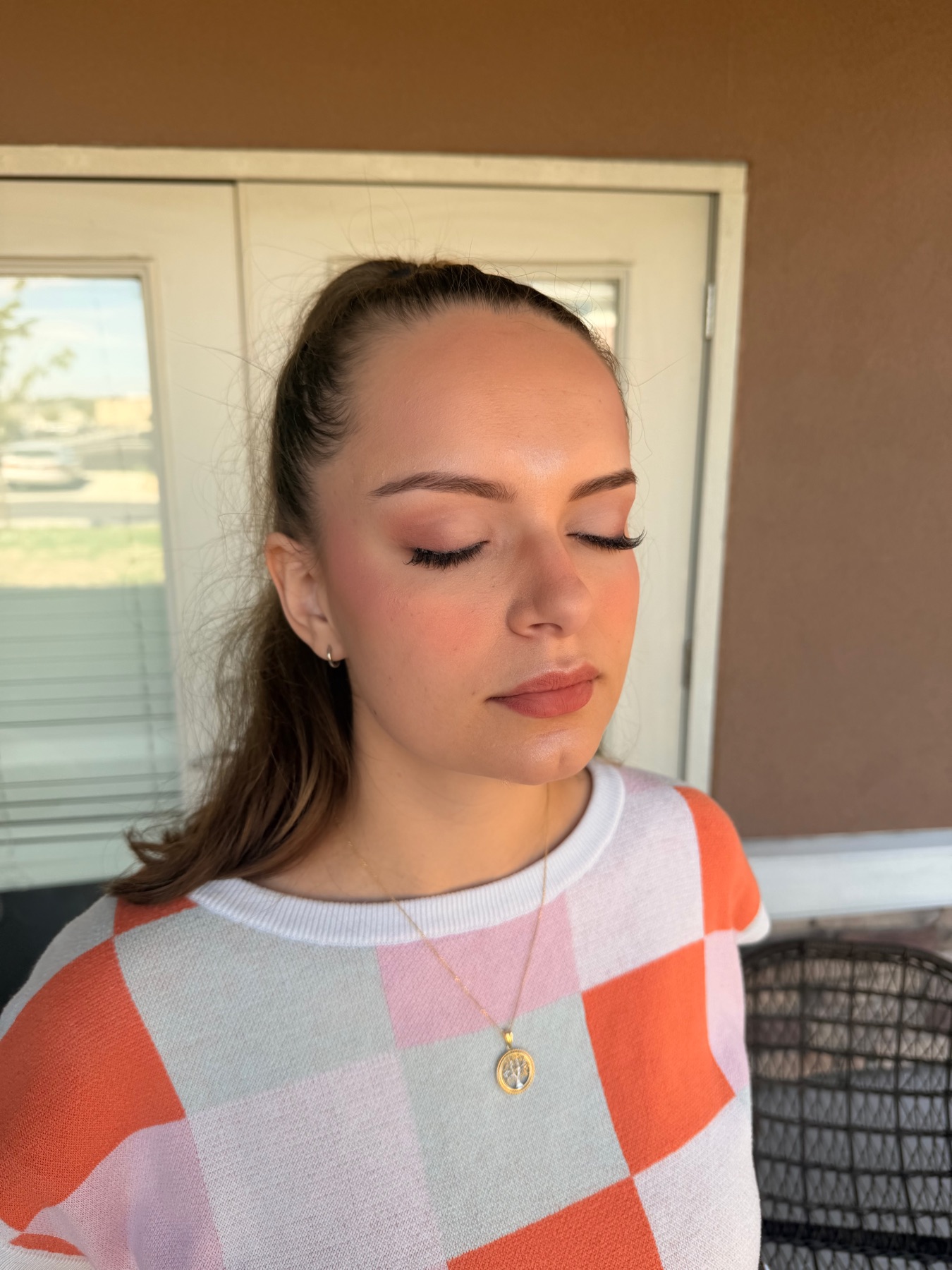 Soft peach glam with a sleek ponytail