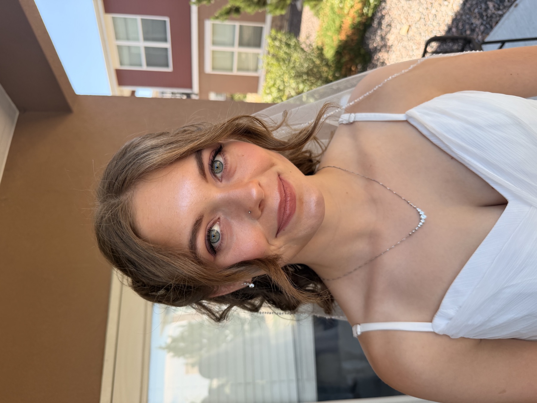 Smiling bride with soft curls, glowing makeup and a veil