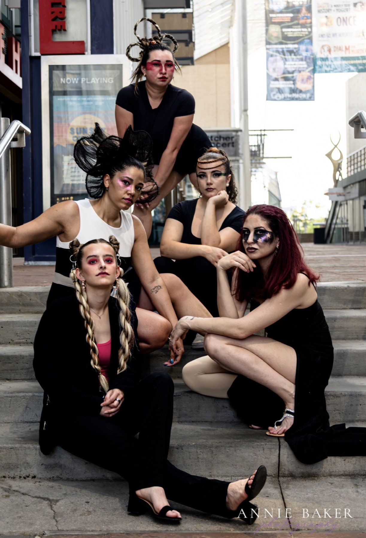 Group of models on city steps with sculptural hair and editorial makeup